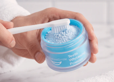 Dipping a damp toothbrush into MySweetSmile teeth whitening powder