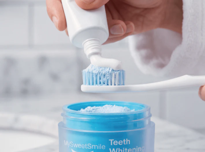 Adding toothpaste over MySweetSmile whitening powder on a toothbrush